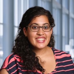 Dr. Monika Kumar wearing a pink and blue striped shirt standing in the Clements University Hospital lobby