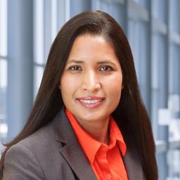 Dr. Ritu Lapsiwala wearing a red shirt and a grey jacket standing in the Clements University Hospital lobby