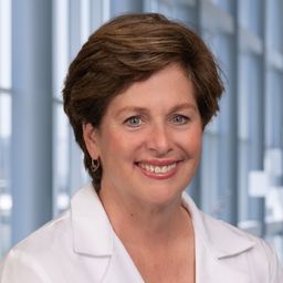 Dr. Elizabeth Maher wearing a white lab coat standing in the Clements University Hospital lobby