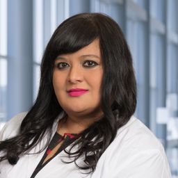 Dr. Alka Mallik wearing a white lab coat standing in the Clements University Hospital lobby