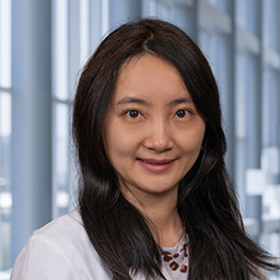 Dr. Bingqing Xie wearing a floral print shirt and a white lab coat standing in the Clements University Hospital lobby