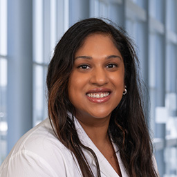 Dr. Jocelyn Abraham wearing a white lab coat standing in the Clements University Hospital lobby