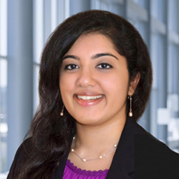 Dr. Lavanya Dharmarajan wearing a purple shirt, and a black suit coat standing in the Clements University Hospital lobby