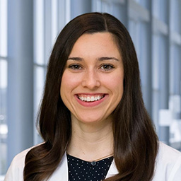 Dr. Lanna Felde wearing a dark patterned shirt, and a white lab coat standing in the Clements University Hospital lobby