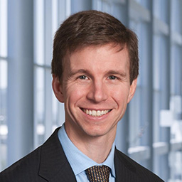 Dr. Stephen Harder wearing a blue shirt with a patterend tie, and a dark suit coat standing in the Clements University Hospital lobby