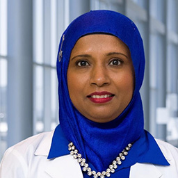 Dr. Muhmuda Islam wearing a bright blue hajib, and a white lab coat standing in the Clements University Hospital lobby