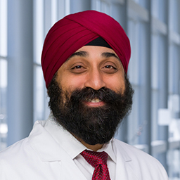 Dr. Sumeet Kalra wearing a white shirt with a maroon tie and matching turban, and a white lab coat standing in the Clements University Hospital lobby