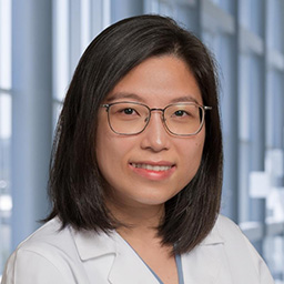 Dr. Tran Nguyen wearing glasses and a white lab coat standing in the Clements University Hospital lobby