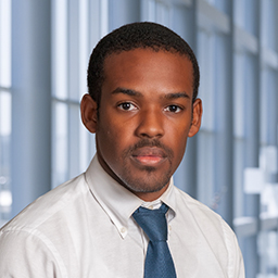 Dr. Kelvin Oliver wearing a white shirt with a blue tie standing in the Clements University Hospital lobby