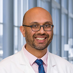 Dr. Vivek Patel, a man wearing wearing a white lab coat and a blue tie