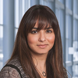 Dr. Farihah Perwez wearing a patterned black and white shirt standing in the Clements University Hospital lobby