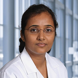 Dr. Asha Rajashekar wearing a white lab coat standing in the Clements University Hospital lobby