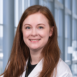 Dr. Hannah Smith, wearing a black shirt and a white lab coat standing in the Clements University Hospital lobby