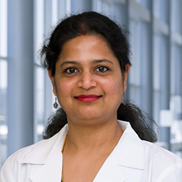 Dr. Sudha Somasundaravelayudham wearing and a white lab coat standing in the Clements University Hospital lobby