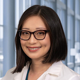 Dr. Jane Xu wearing glasses, a and a white lab coat standing in the Clements University Hospital lobby