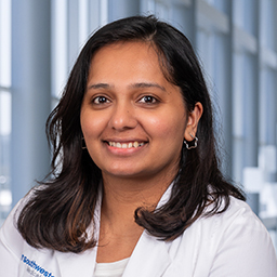 Binnu gangadharan wearing a white lab coat standing in the Clements Univeristy Hospital lobby