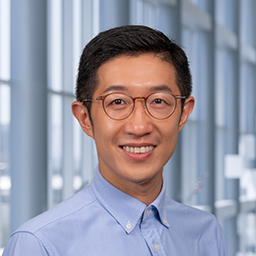 Dr. Cheng Han wearing glasses and a blue shirt standing in the Clements University Hospital lobby