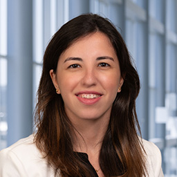 Dr. Marie Christelle Saade wearing and a black shirt and a white jacket standing in the Clements University Hospital lobby