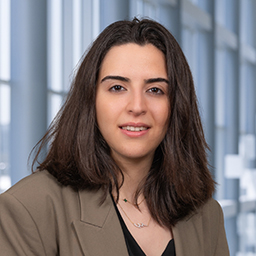 Dr. Nour Younis wearing a black shirt and taupe jacket standing in the Clements University Hospital lobby