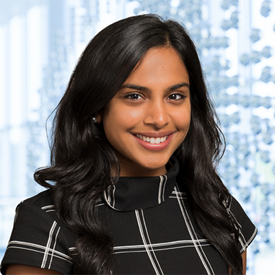 Dr. Niharika Neela wearing a black and white plaid dress standing in the Clements University Hospital lobby
