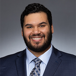 Nickholas Sevey wearing a light blue shirt with a patterned necktie and a dark jacket