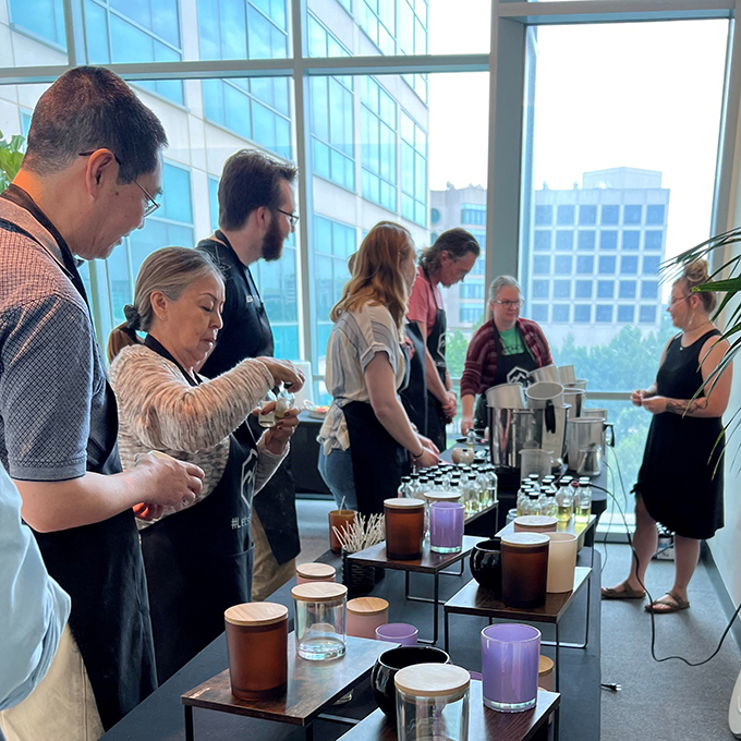 People lined up at a table containing materials for diy candles