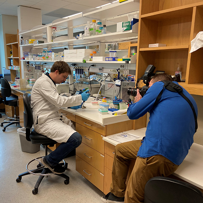 Photographer takes shots of person working in a lab setting
