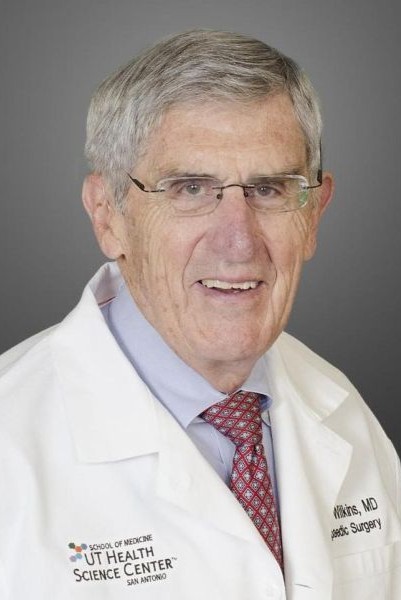 Dr. Kaye Wilkins grey-haired doctor with glasses wearing white coat and tie