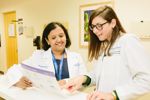 Alumni looking at a chart Two female doctors look at a chart