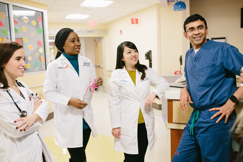 Alumni having adiscussion in hospital Three female and a male doctor have a discussion in a hospital hallway