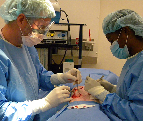 Two people in surgical scrubs performing an operation.