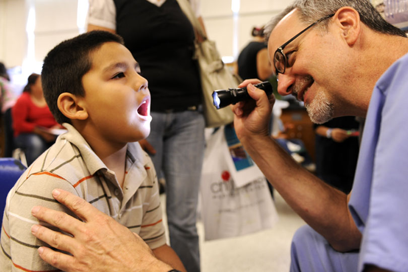 A medical student looks a child's throat during a clinic at United to Serve. A medical student looks a child's throat during a clinic at United to Serve