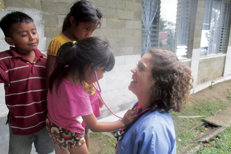 A young girl listens to a medical student's heart. A young girl listens to a medical student's heart with a pink stethoscope.