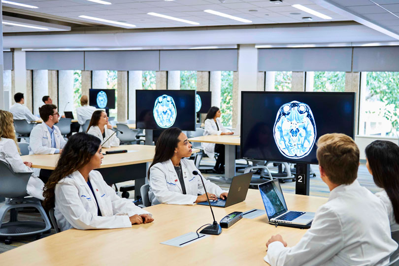 Medical students look at a scanned image of a brain on video monitors in the Team-Based learning Center Medical students looking at a scanned image of a brain on video monitors in the Team-Based learning Center