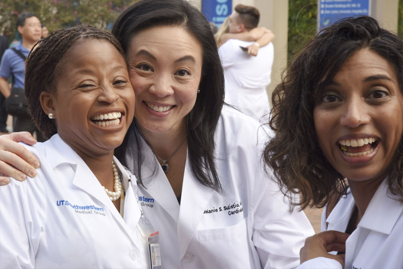 Faculty and administrators at the White Coat Ceremony. Three faculty and administrators are happy at the White Coat Ceremony