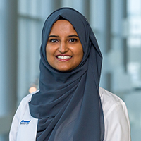 woman wearing a blue headscarf and a white coat with UT Southwestern Medical Center logo