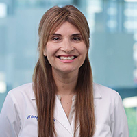 woman with long, brown hair wearing a white shirt and white coat with UT Southwestern Medical Center logo