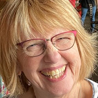 woman with short blonde hair wearing red glasses