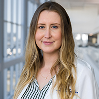 woman with long, wavy blonde hair wearing a blue shirt and white coat with UT Southwestern Medical Center logo