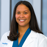 woman with long, dark hair wearing a royal blue shirt and white coat with UT Southwestern Medical Center logo