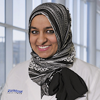 woman wearing a black and white patterned headscarf and white coat