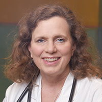 woman with shoulder-length curly brown hair wearing a white coat