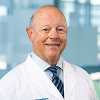 bald man wearing a blue and white striped shirt, black and blue striped tie, and white coat