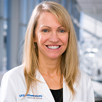 woman with shoulder length blonde hair wearing a black shirt and white coat with the UT Southwestern Medical Center logo