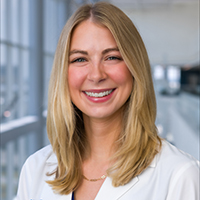 woman with shoulder-length blonde hair wearing a white coat