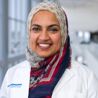 woman wearing white, gold, red and blue patterned headscarf and white coat with UT Southwestern Medical Center logo