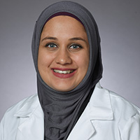 woman wearing grey headscarf and white coat