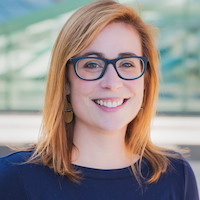 woman with shoulder-length auburn hair wearing a black shirt and black glasses