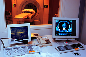 Aston Center PET CT CT suite seen through window; desk in foreground shows scans on computer monitors