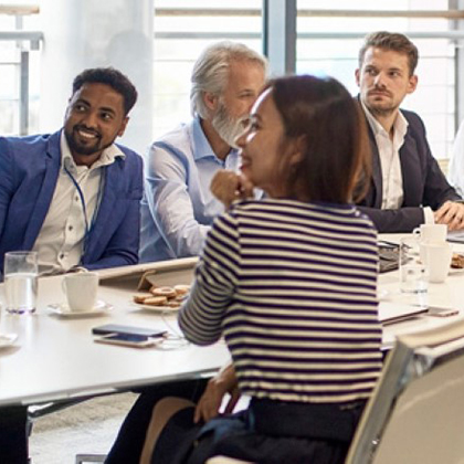 bright meeting room with 4 smiling adults seated at long table